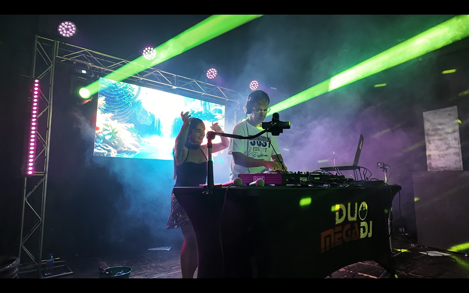 Duo MegaDJ tocando ao vivo, Adelino e Sandra nos equipamentos com luzes coloridas